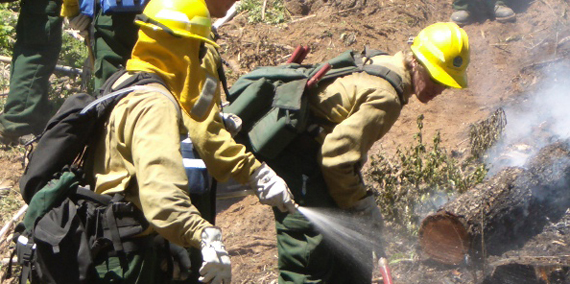 Young firefighters spray water on fire